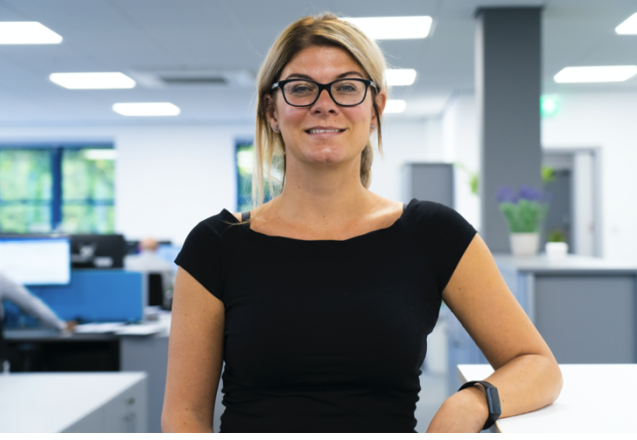 A woman in a black top smiling in an office